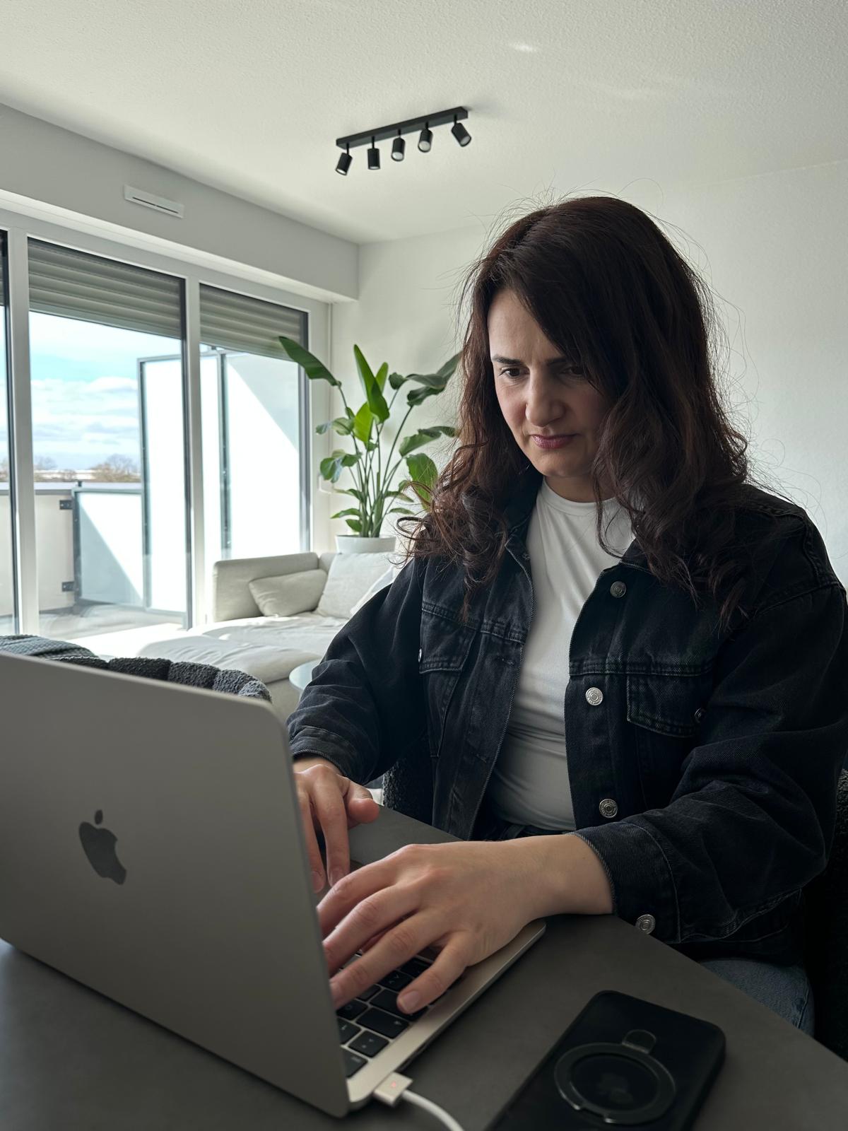 Afag Askerova arbeitet an einem Laptop an einem hellen Tisch.