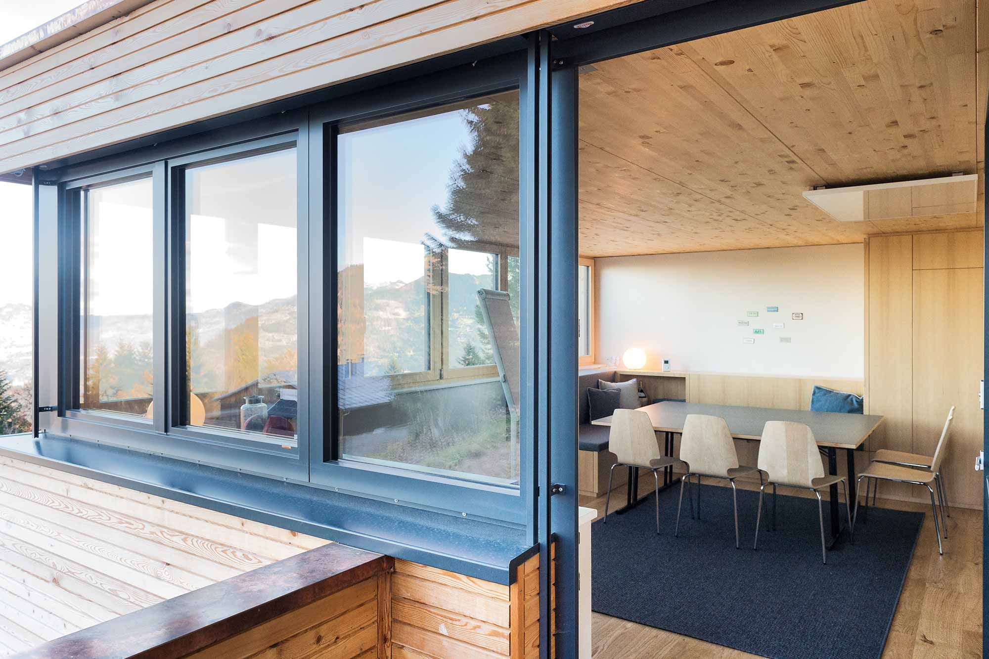 Heller Seminarraum mit Holzinterieur, Tisch, Stühlen und Flipchart.